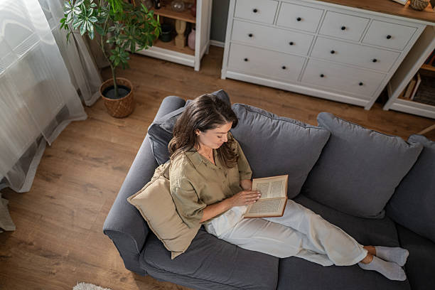 istock Woman relaxing at home reading book on sofa 2237151878