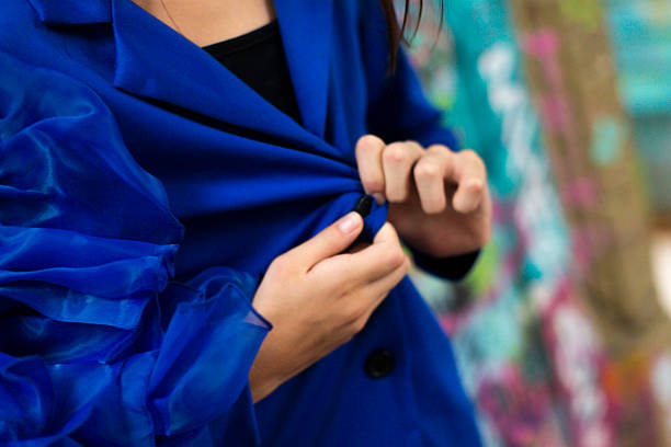 A person adjusting their blue jacket with sheer sleeves, showcasing style