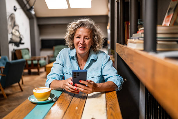 istock Smiling mature woman using smartphone in cafe 2237158236