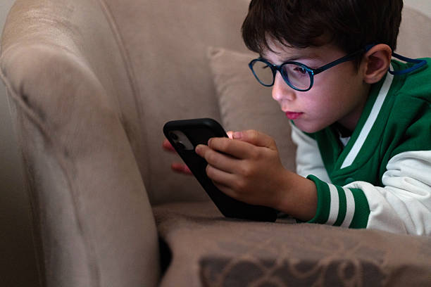 istock Boy with glasses playing on mobile phone 2237159569