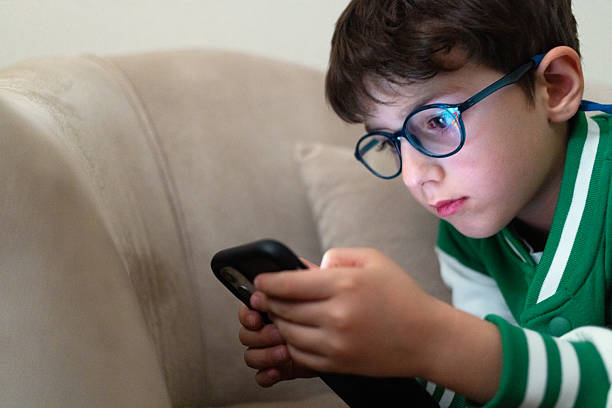 istock Boy with glasses playing on mobile phone 2237159570