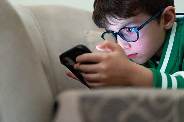 istock Boy with glasses playing on mobile phone 2237159571