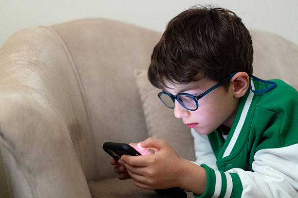 istock Boy with glasses playing on mobile phone 2237159950