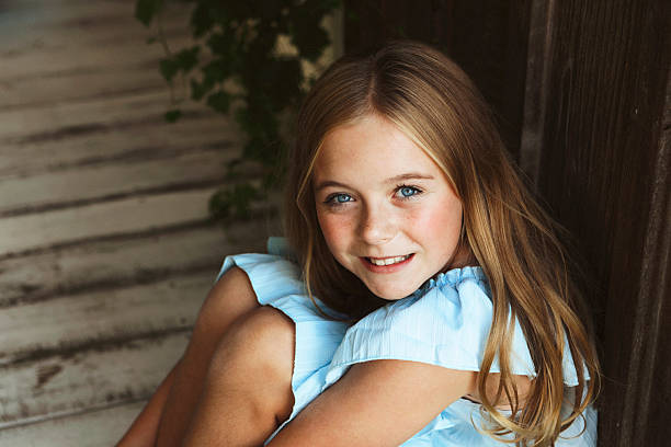 A beautiful girl, 10 years old, posing for a picture on a porch. Shot with a Canon 5D Mark IV.