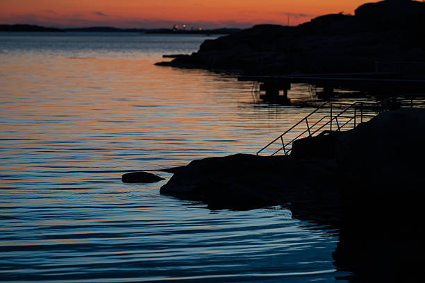 Peaceful rocky coastline at dusk with ladder.
