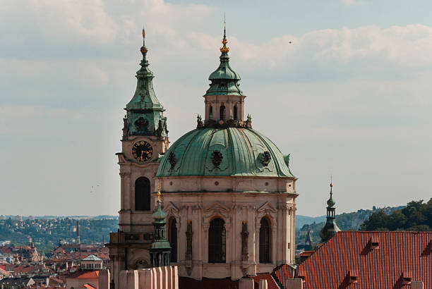 Prague, Czech - August 22, 2013 - St. nicholas church dome and clock tower in prague's skyline under blue sky.