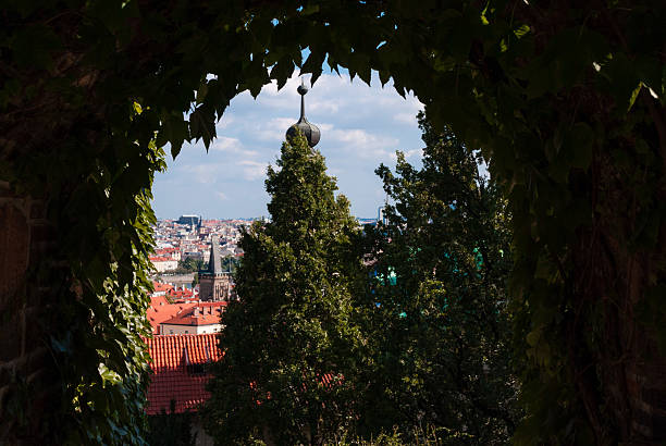 Prague, Czech - August 22, 2013 - Scenic cityscape view framed by leafy archway and towering trees.