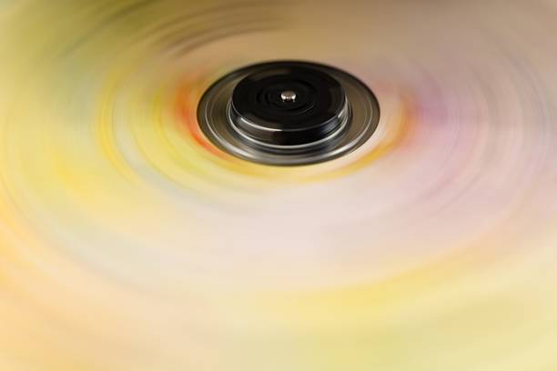 Abstract close-up of a rotating compact disc with vivid yellow and pink motion blur, creating a colorful circular background and dynamic futuristic effect.