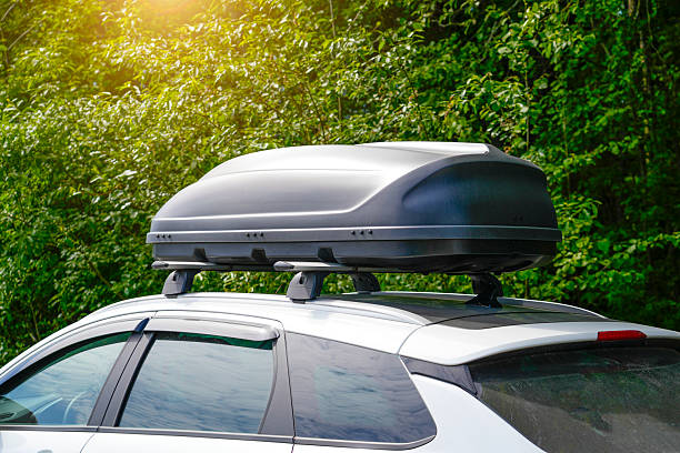 istock A white vehicle has a roof box securely mounted on top. The container appears to be made of durable plastic, and is being used for travel and additional storage. Trees are visible in the background 2237180231