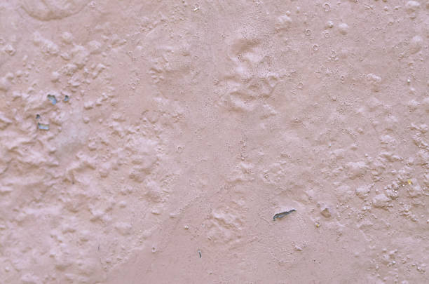 A rough, unevenly textured wall with peeling paint and cracks, creating a weathered and aged background perfect for conveying themes of urban decay and imperfection.