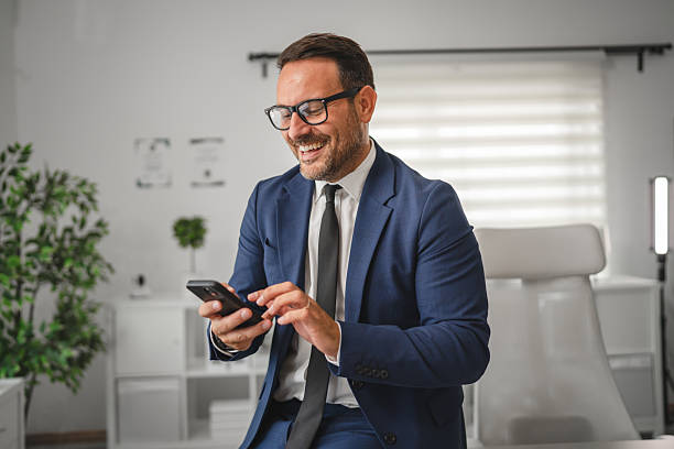 istock Businessman smiling, using smart phone at modern office 2237184565