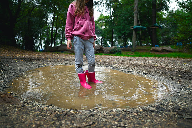 Young girl splashing and having fun in a muddy puddle outdoors