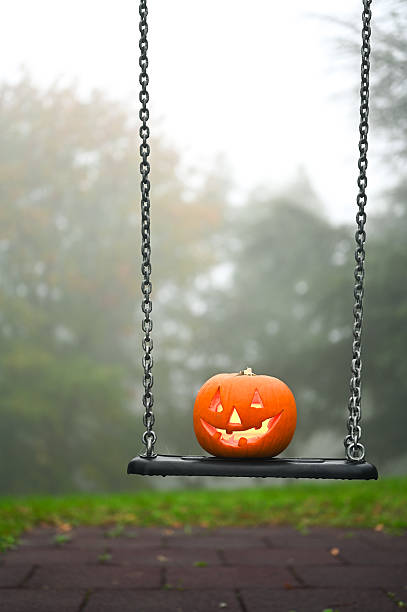 istock Jack-o'-lantern sitting on a playground swing in fog 2237186444