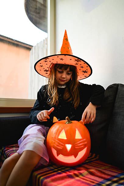 istock Girl wearing witch hat with jack-o'-lantern cat pumpkin 2237187467