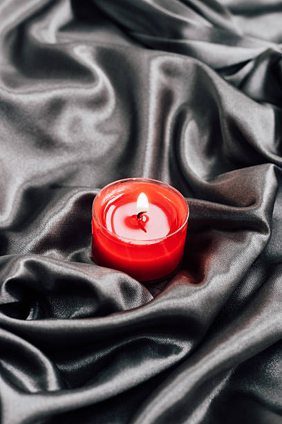 Vibrant red candle set atop smooth black fabric creates a calming atmosphere