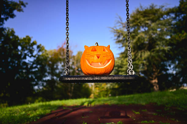 istock Carved cat pumpkin sitting on a swing for halloween 2237187594