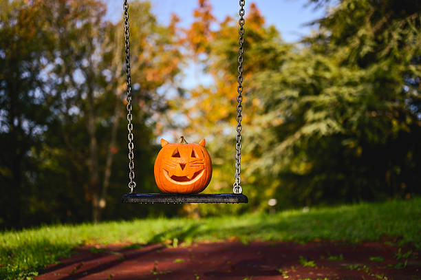 istock Halloween pumpkin jack-o'-lantern swinging in autumn park 2237187632