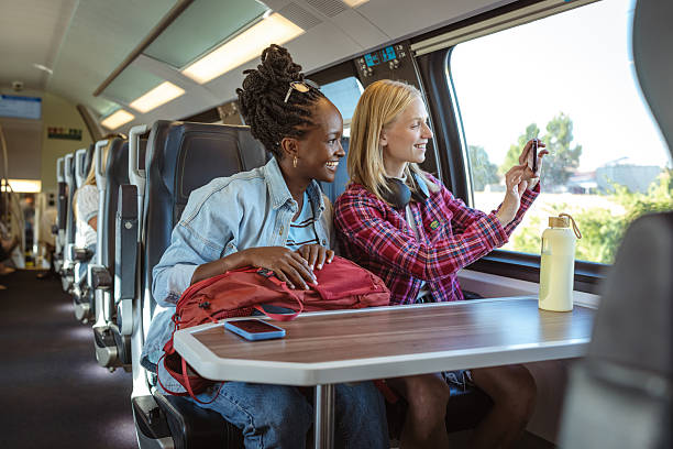 istock Two friends ride a train, sharing photos and conversation at a sunny window table 2237189133