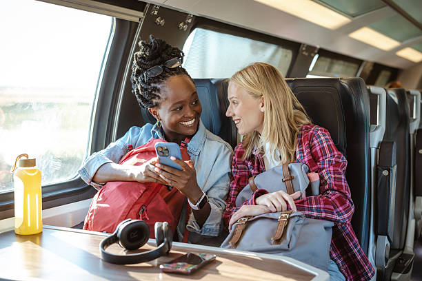 istock Two friends on a train share a joyful moment while looking at a phone during travel 2237189628