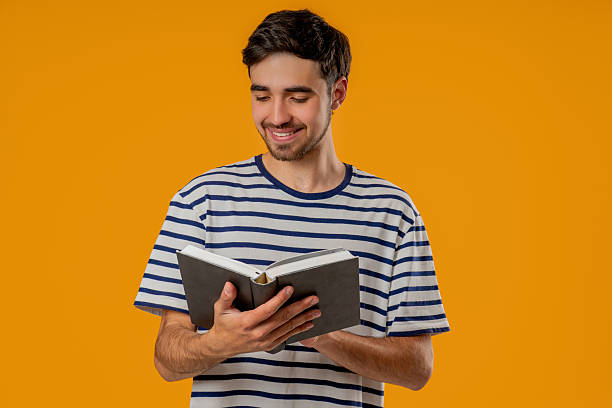 istock Young slavic man reading book with focused smile on yellow background. Discovery time 2237194786