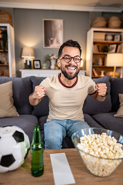 istock Excited man watching soccer game at home celebrating victory 2237202633