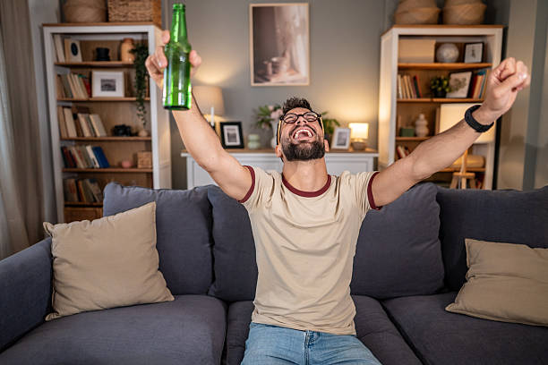 istock Man cheering while watching sports and holding beer bottle 2237202666