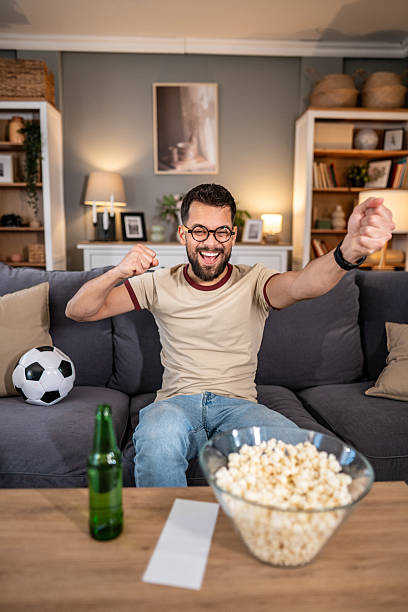 istock Man watching soccer match experiencing triumph in living room 2237202756