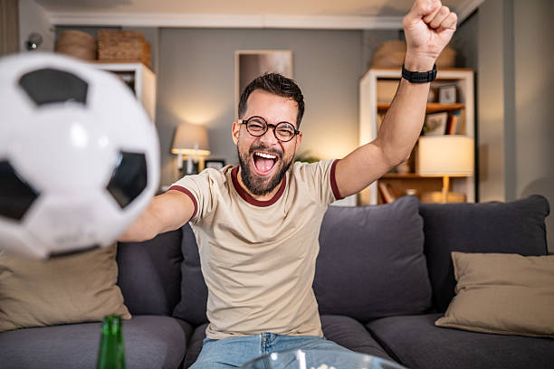 istock Man cheering goal while watching soccer at home 2237202773