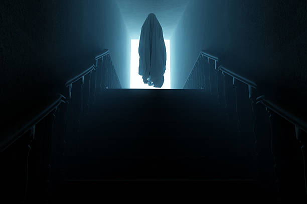 Silhouette of a hooded man with his hands raised menacingly behind a transparent curtain. Concept of demons, paranormal phenomena, ghosts, zombies.