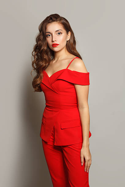 istock Beautiful young woman in red suit standing against white studio wall background 2237211754
