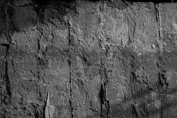 Gray textured stone wall with sunlight shadows for architecture and background concept