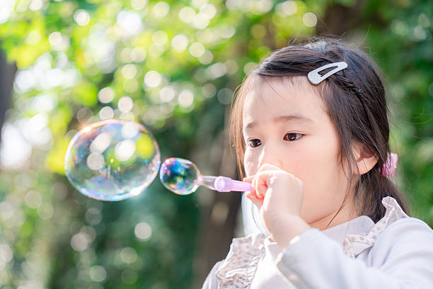 istock Little girl playing with soap bubbles 2237216269