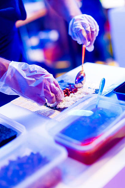 Gloved Hands Preparing Spooning Topping onto a Street Food Sushi Roll