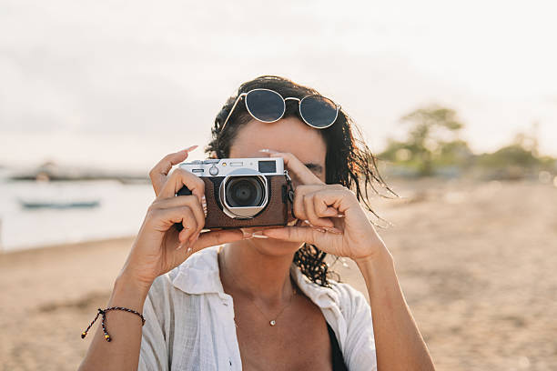 istock Woman holding retro camera on beach during summer travel 2237222214