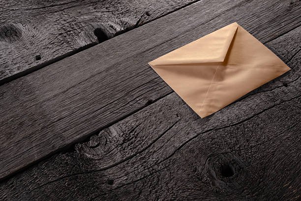 A sealed brown craft envelope placed on a wooden surface with detailed texture. File with Clipping Path