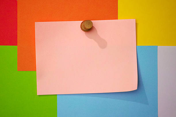Blank pink note paper, pinned to a colorful array of background blank message notes. Conceptual blank message sign. Good copy space.