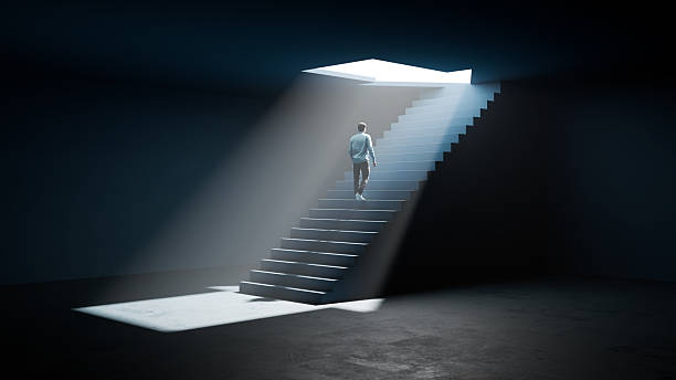 istock Man Walking Up Stairs From Darkness Toward Glowing Arrow Light - Success, Hope, and Ambition 3D Render 2237241021
