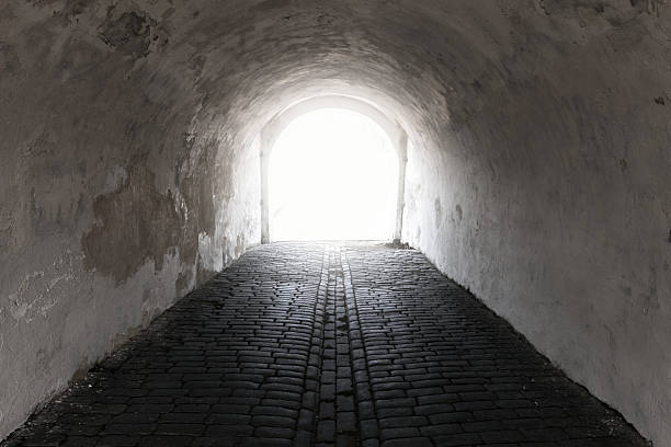 istock A dim, weathered tunnel with a cobblestone floor and curved white walls 2237243319