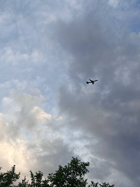 istock Airplane Flying Through Cloudy Sky During Late Afternoon With Trees Below 2237244337