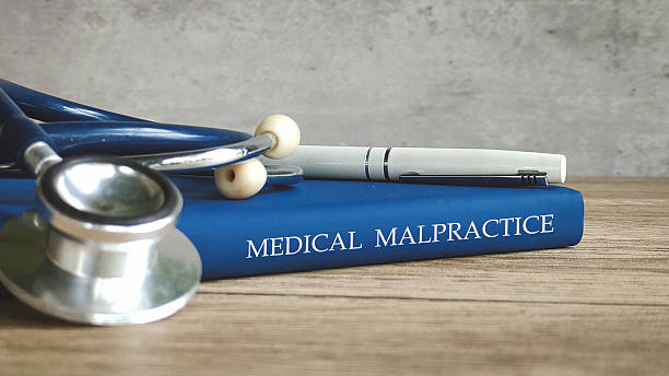 Stethoscope and a pen on a book titled MEDICAL MALPRACTICE, representing legal issues in healthcare. stock photo
