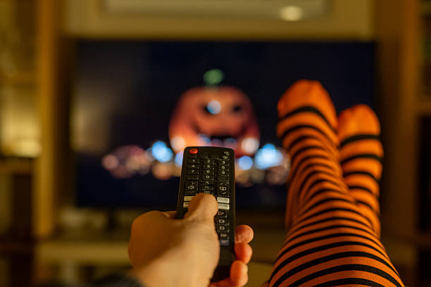 istock Streaming platform on Halloween night, cozy autumn atmosphere with striped socks, remote control and blurred TV in seasonal lifestyle scene. 2237249347