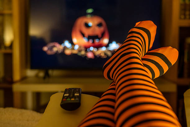 istock Halloween streaming in cozy home setting, orange striped tights, blurred television screen, lifestyle indoors and warm seasonal vibes. 2237249363