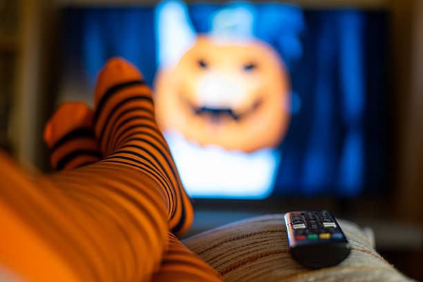 istock Watching streaming platform during Halloween night, festive cozy vibes at home with orange striped tights, blurred TV and remote control. 2237249454