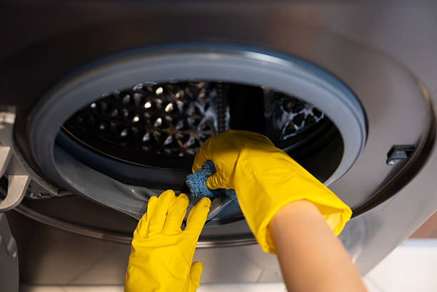 istock Close-up of gloved hands wiping inside washing machine drum. 2237252526
