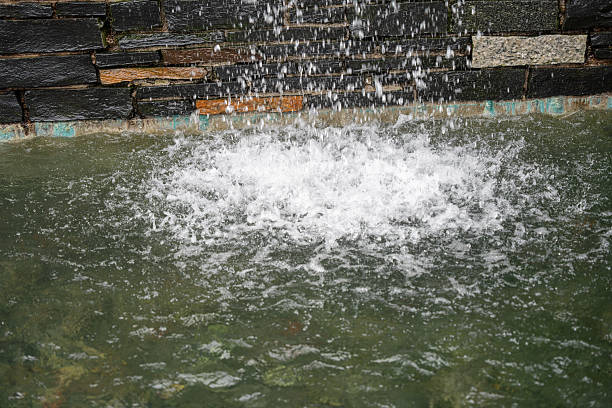 Bubbling water cascades from a stone wall into a pool.