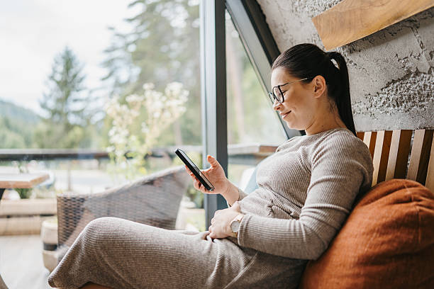 istock Smiling expectant mother using smartphone at home 2237263100