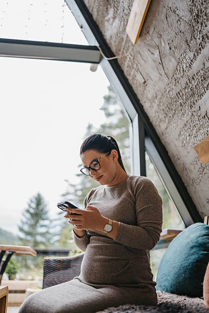 istock Pregnant woman using smartphone indoors 2237265635