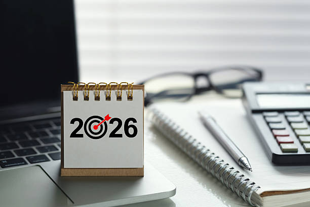 istock Desk calendar showing 2026 with a target icon on an office workspace beside calculator, notebook, pen and laptop, symbolizing financial planning, budgeting, goals and KPI strategy for the new year. 2237268893