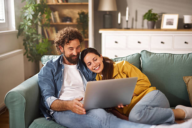 istock Happy couple relaxing on sofa browsing internet on laptop at home 2237269265