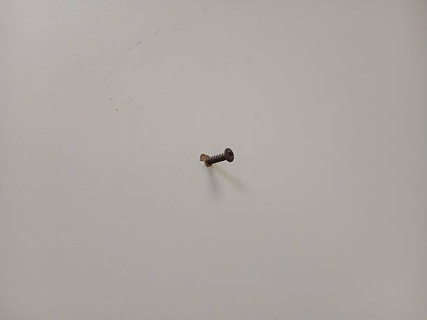 istock Small metal nail in a yellow wall, close-up view 2237271195